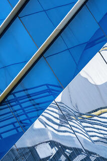 Blue, white, and gray lines distorted in glass of modern architecture