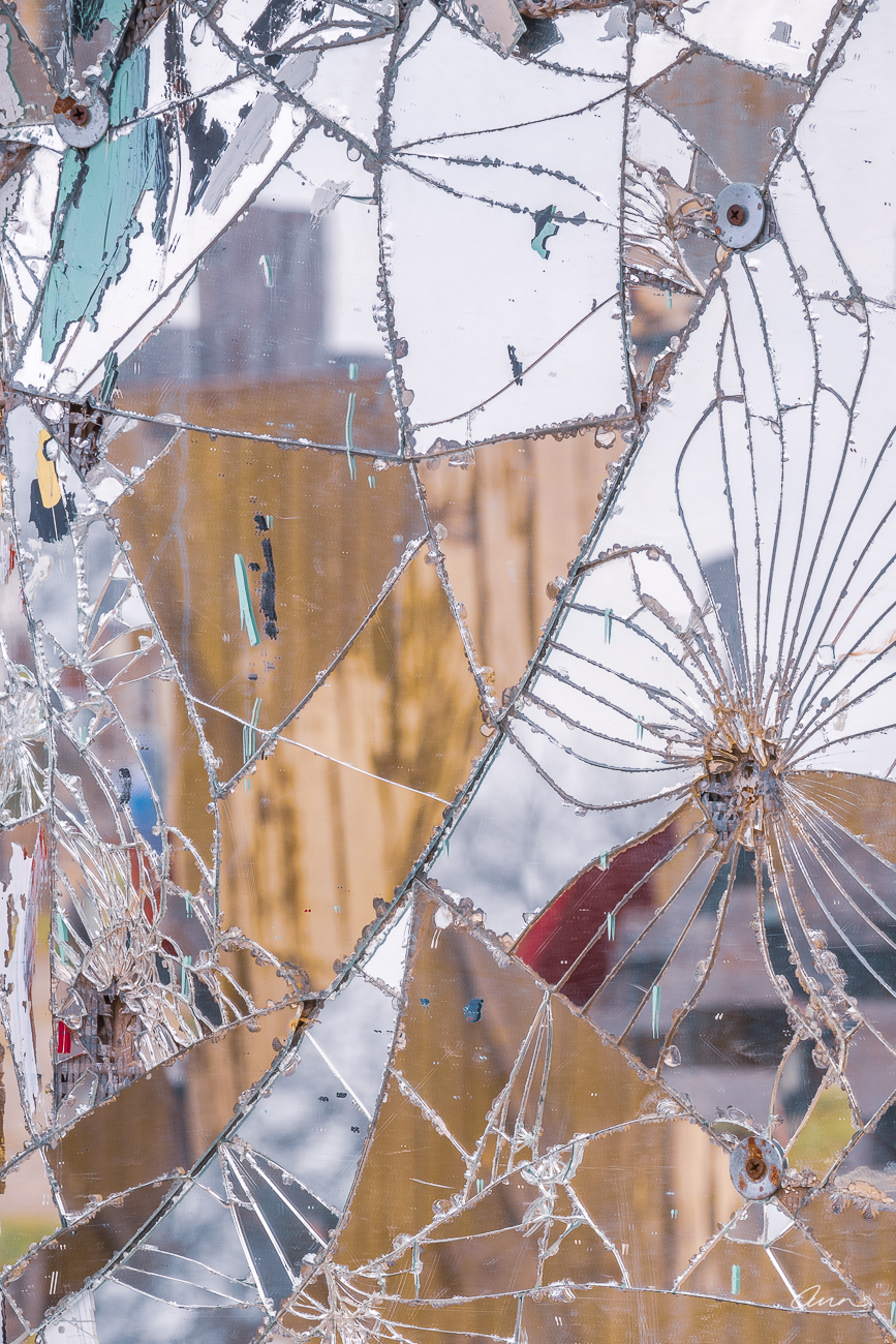 Close-up of broken mirror with a flower pattern that reflects colors and shapes.