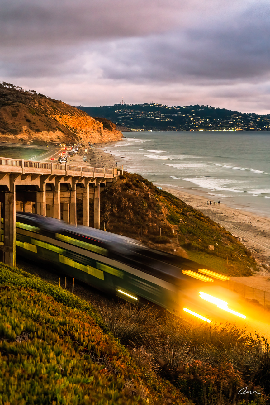 The California Coaster rushes by Torrey Pines State Beach carrying commuters at sunset. How many of them look longingly at the...